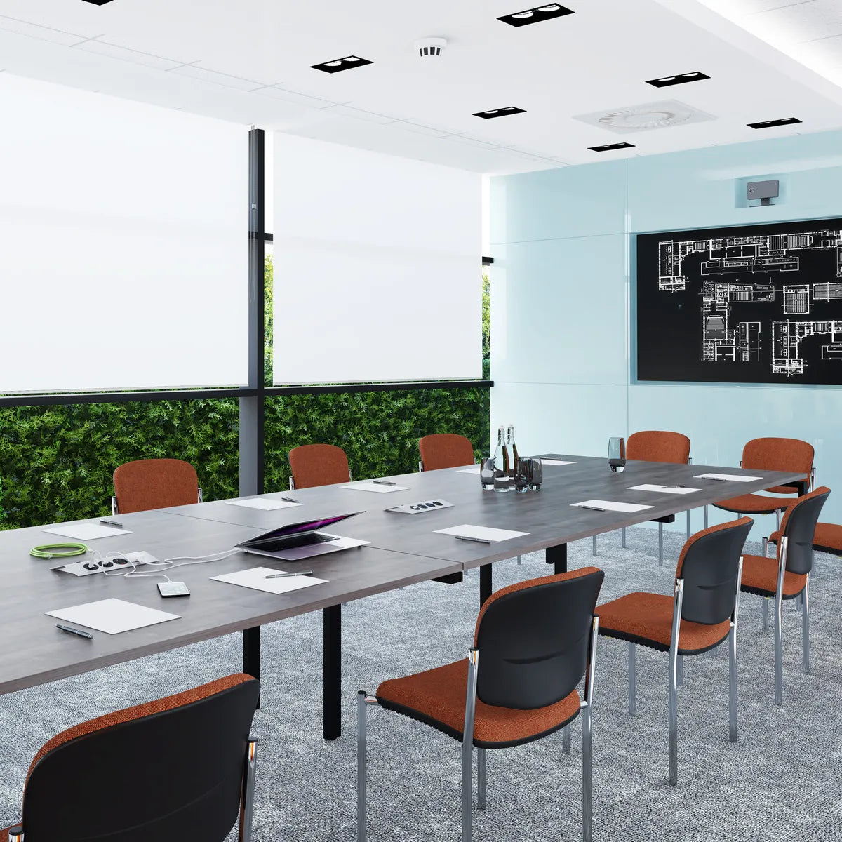 Boardroom with a long grey meeting table, orange-seat chairs and a green living wall